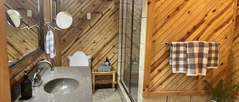 Un baño con pared de madera, un lavabo, un inodoro y una zona de ducha.