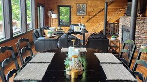 Un intérieur en bois comprenant une table à manger, des chaises, un lustre et une cheminée.