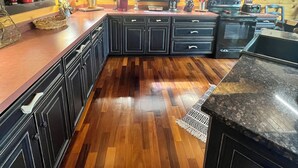 Une cuisine moderne avec des meubles de couleur sombre, un plancher en bois et un îlot central.