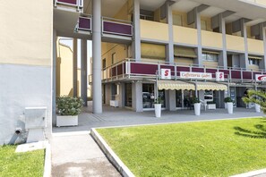 Een meerhoog gebouw met een café op de begane grond genaamd 'Caffetteria Gabri' en een zichtbaar buitenterrein met zitplaatsen.