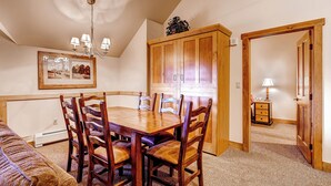 A dining area with a wooden table and chairs, a chandelier, and a framed picture on the wall. - River Run Village |  Cozy 1BR for 6 | Pool Access (Keystone)