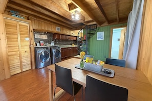 Uma cozinha compacta com armários de madeira, máquina de lavar roupa e uma área de refeições com mesa e cadeiras.