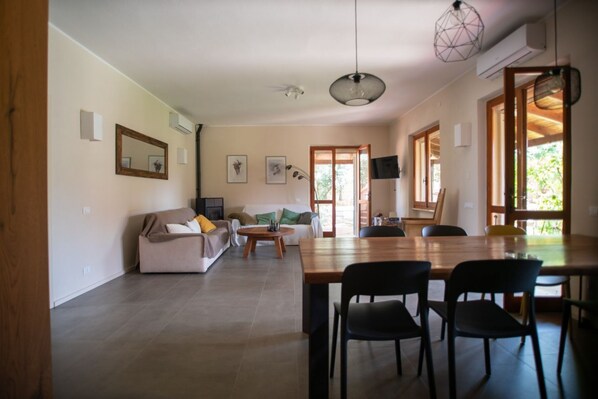 Amplia sala de estar con sofá, mesa de centro y mesa de comedor con sillas.
