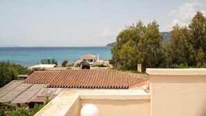 Une propriété située sur la côte, dotée d’un toit en tuiles, offrant une vue sur la mer et s’ouvrant sur un paysage montagneux.