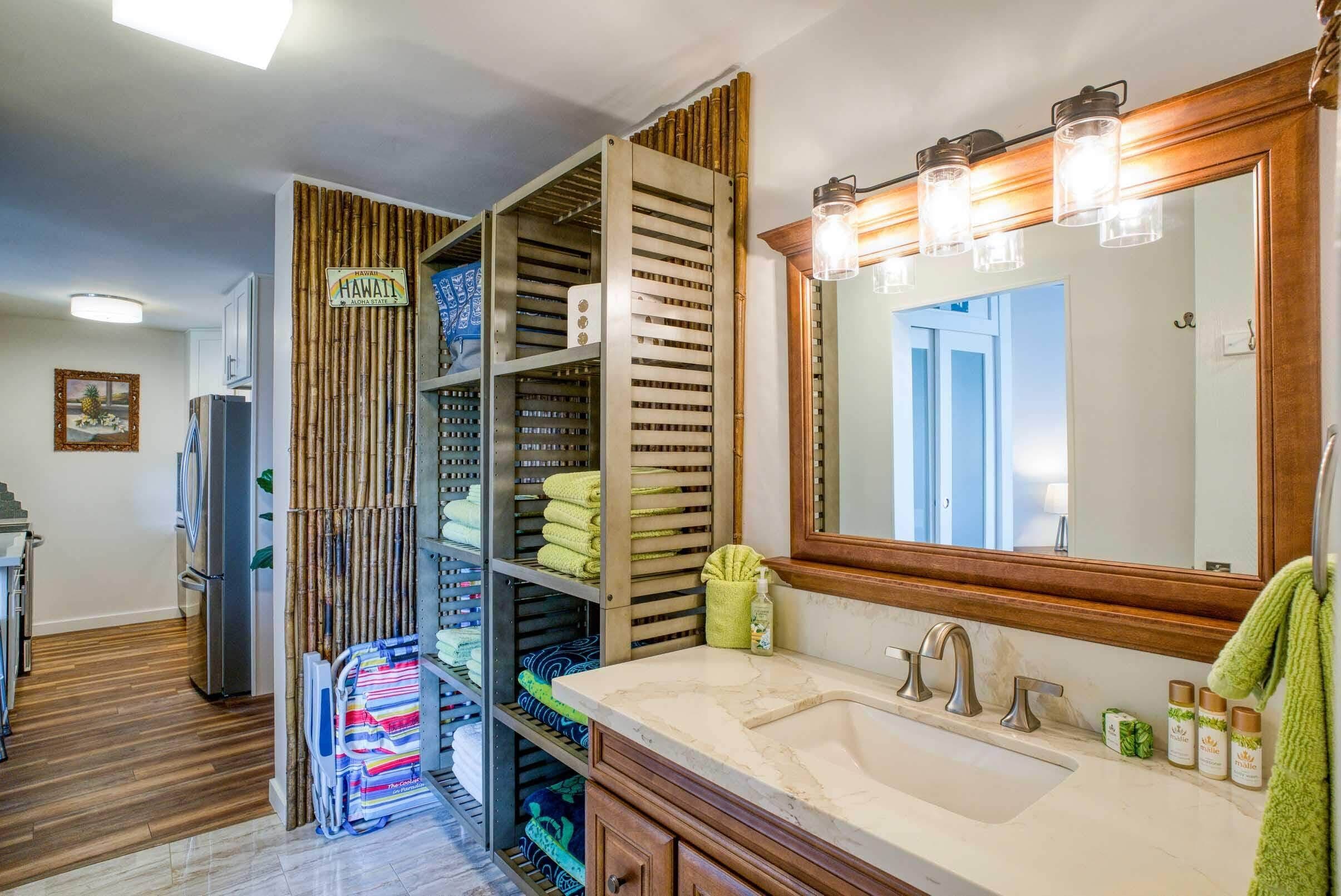A bathroom with a large mirror, a sink, and shelves with towels and toiletries.