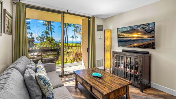 A living room with a sofa, coffee table, and a painting of a sunset.