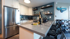 A modern kitchen with stainless steel appliances, a built-in microwave, and a wine bottle on the counter.