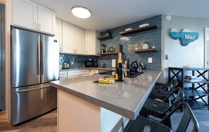 A modern kitchen with stainless steel appliances, a built-in microwave, and a wine bottle on the counter.