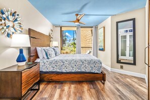 A bedroom with a bed, wooden nightstand, and a ceiling fan.
