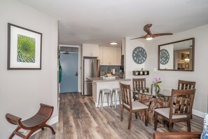 A modern kitchen with white cabinets, stainless steel appliances, and a dining area with wooden chairs and a glass table.