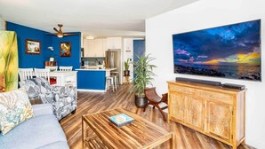 A living room with a blue accent wall, a wooden coffee table, a sofa, and a TV on the wall.