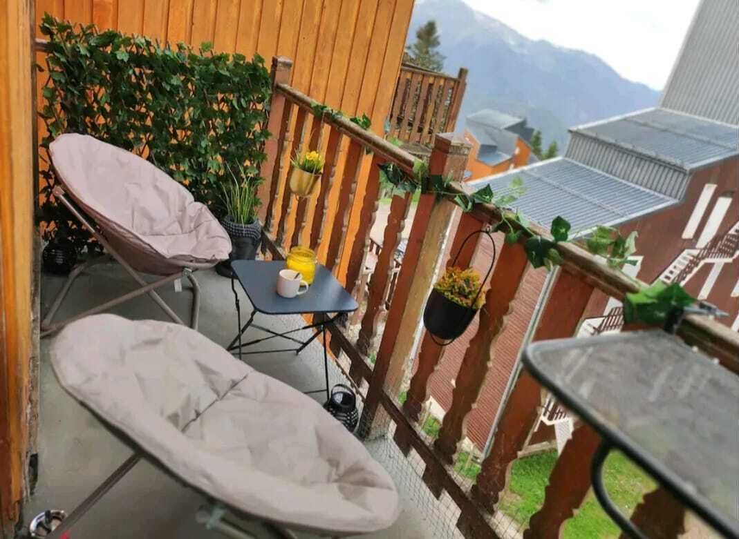 Un balcon avec une chaise, une petite table et des plantes en pot.
