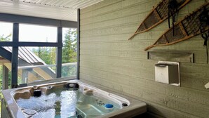 A hot tub in a room with a wooden wall and a large window. - The Bear's Den Ski Chalet/Private Hot Tub/Ski In+Out/with Parking/Pet-Friendly! (Big White)