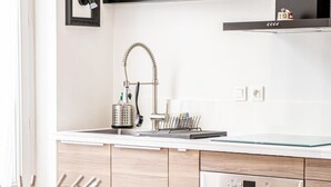Una cocina moderna con horno empotrado, un lavamanos con un grifo original y una zona de comedor con mesa y sillas.