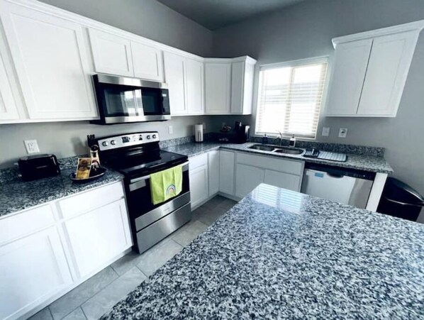 Enjoy cooking in this well-equipped kitchen with a granite island, stainless steel oven, and sink with a window above.