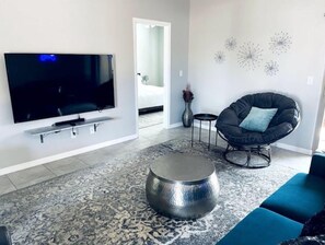 Relax in this stylish living room with a flat-screen TV, comfortable chair, and vibrant rug.