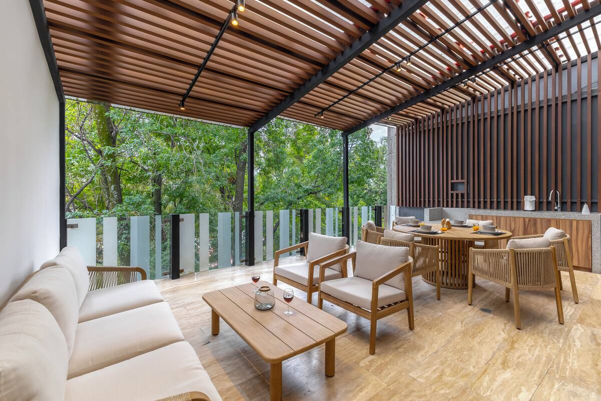 An outdoor seating area with a wooden table, chairs, and a sofa.