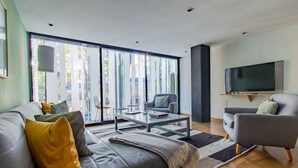 Una sala de estar moderna con un sofá gris, una mesa de centro y un televisor montado en la pared.