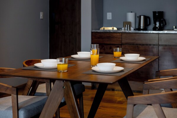 A dining table set with bowls and glasses of orange juice, wooden chairs, and a kitchen area in the background. - Capitalia Temistocles Polanco (Mexico City)