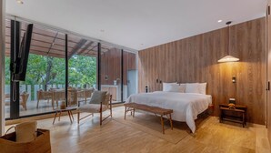 Un dormitorio moderno con una cama grande, suelo de madera, una zona de comedor con sillas y vistas amplias a través de grandes ventanales.