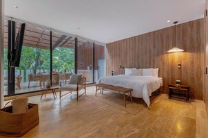 Un dormitorio moderno con una cama grande, suelo de madera, una zona de comedor con sillas y vistas amplias a través de grandes ventanales.