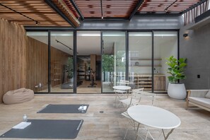 A modern interior with a glass door leading to a dining area, a seating area with a white table and chairs, and a large potted plant.