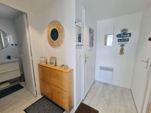 Hotellihuone, jossa on puinen kaappi, peili, koristeellinen seinäelementti, kyltillä varustettu ovi ja patteri.