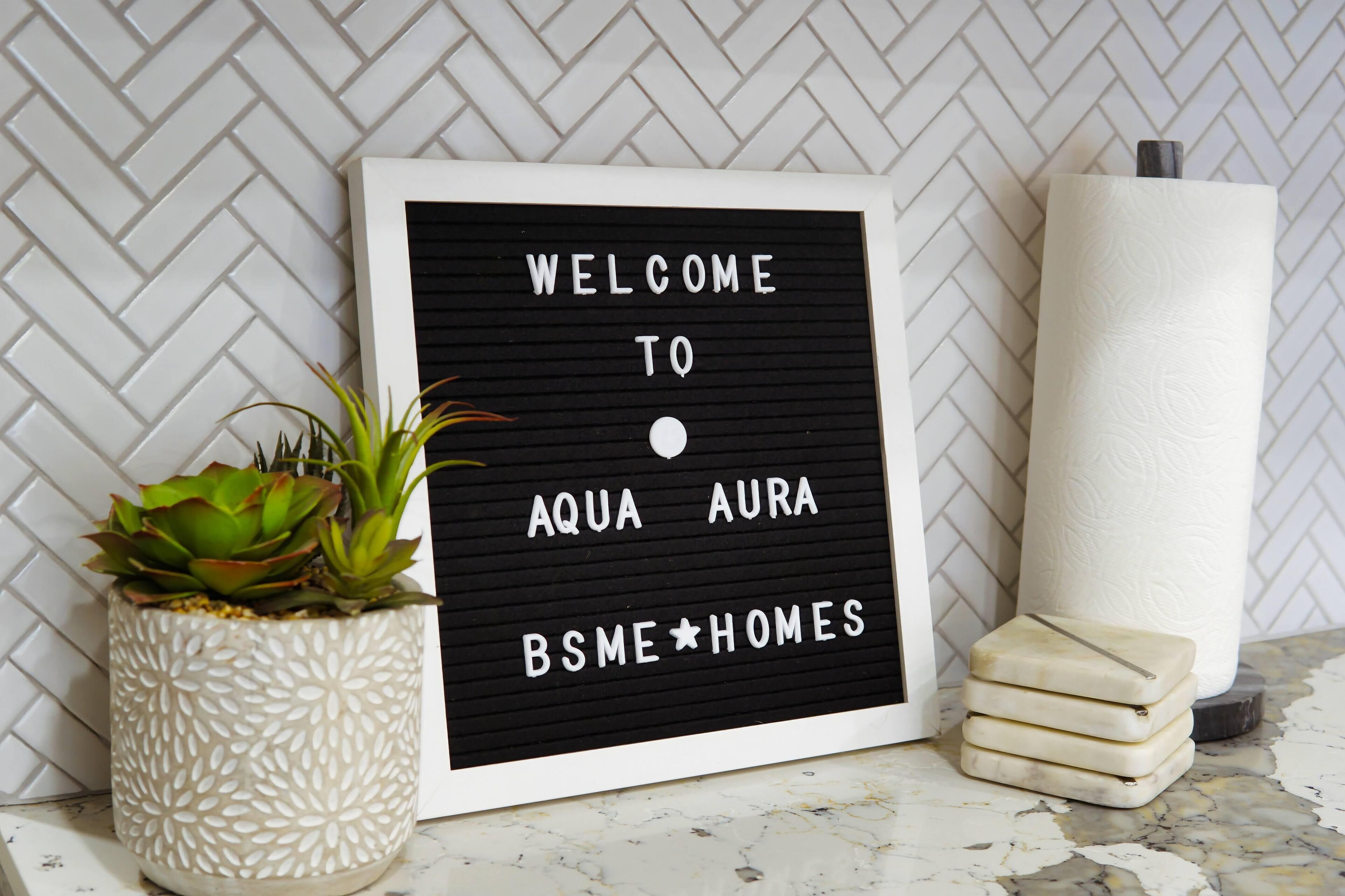 A framed welcome sign with a succulent plant and a candle next to it.