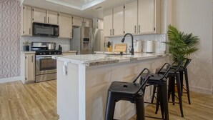 Una cocina moderna con una isla central, electrodomésticos de acero inoxidable y un salpicadero de baldosas en espiga.