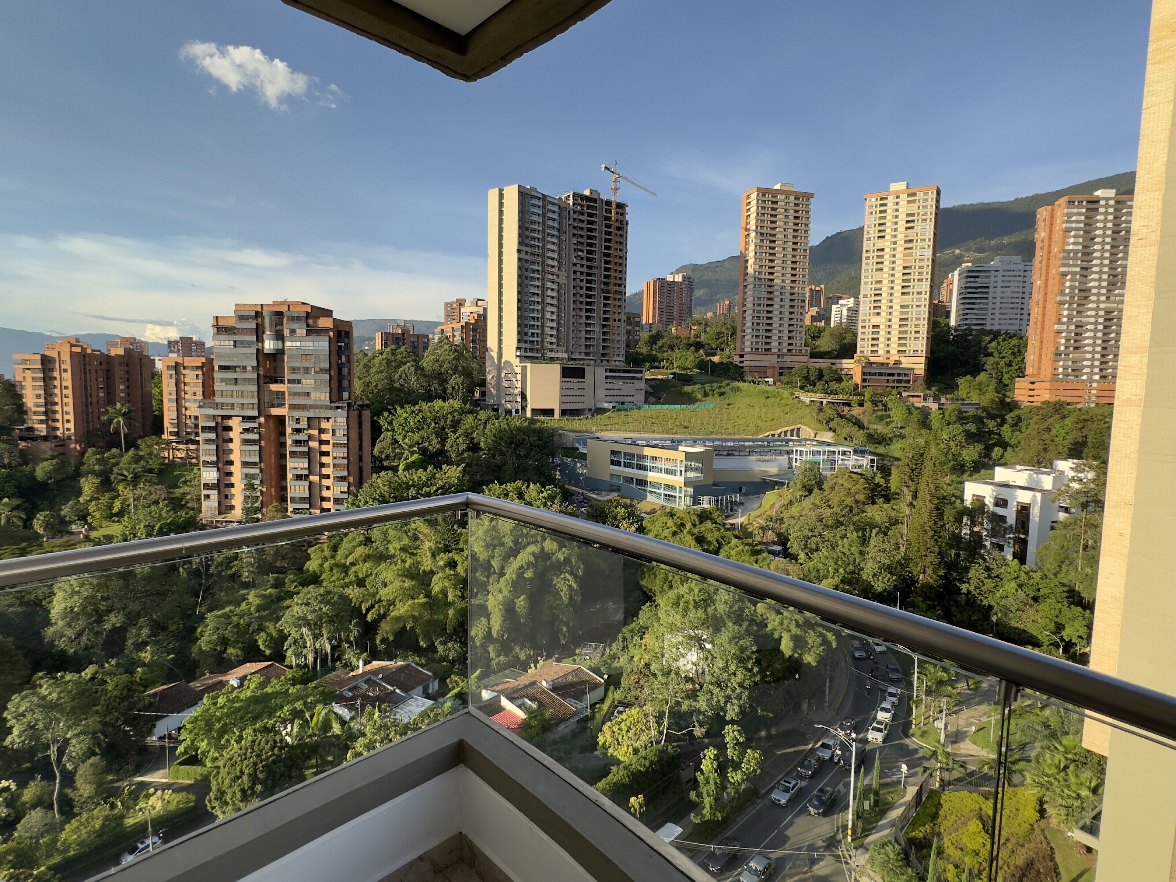 A high-rise building with multiple floors, surrounded by greenery and other residential buildings.