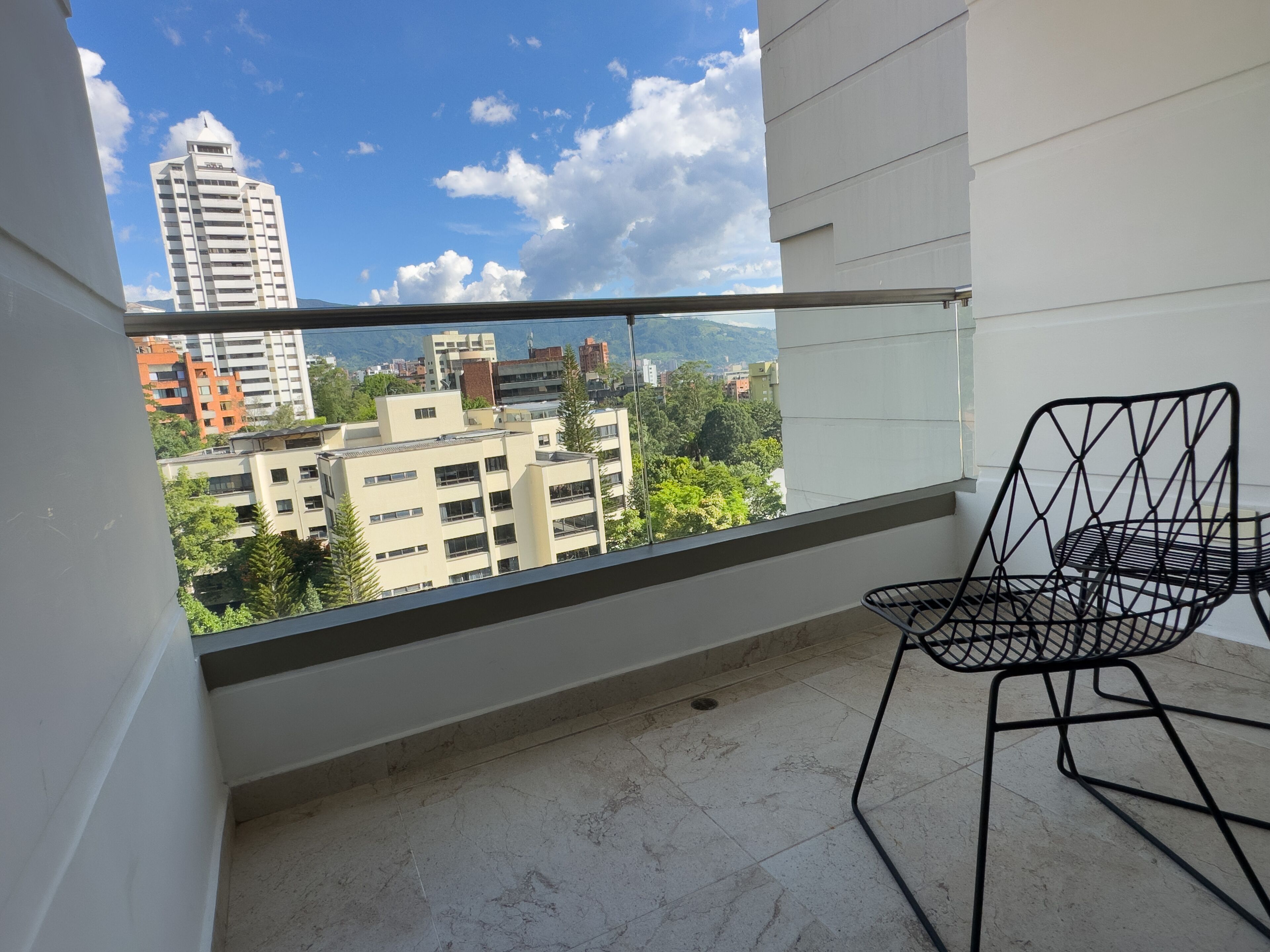 Een balkon met een helder uitzicht op omliggende gebouwen en groen.