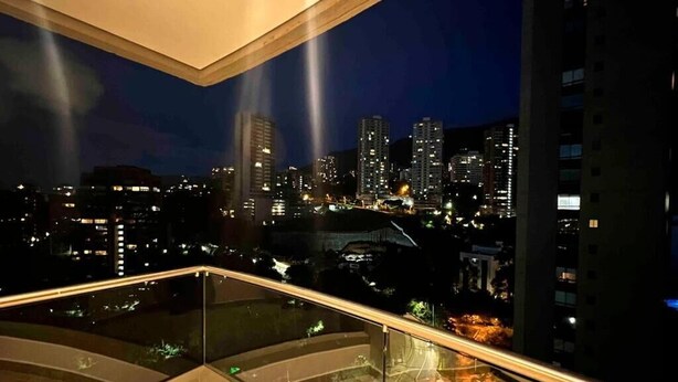 Ein nächtlicher Stadtblick von einem Balkon mit Glasgeländern.