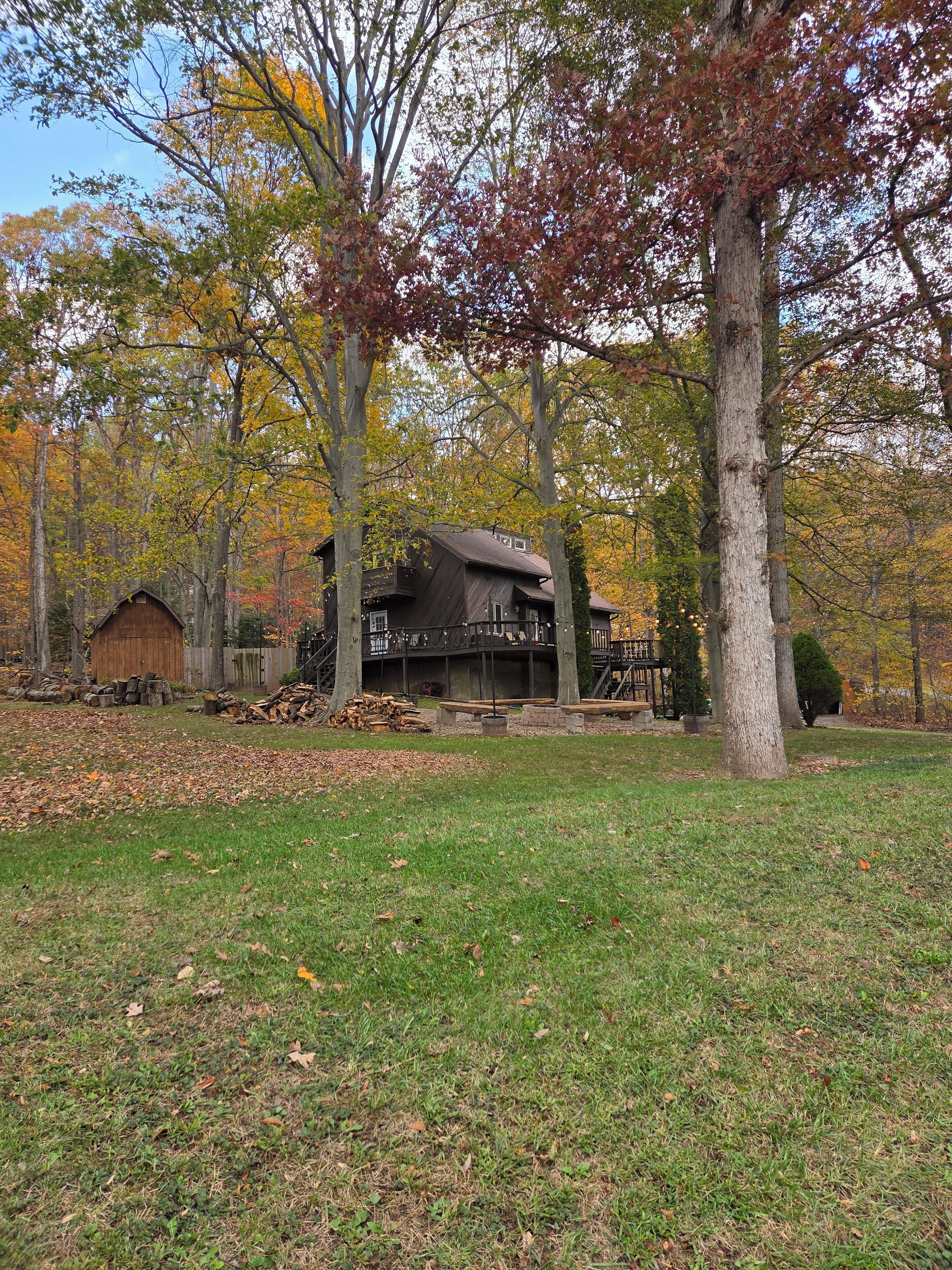 Un chalet rustique doté d’une terrasse, entouré d’arbres aux feuilles d’automne.