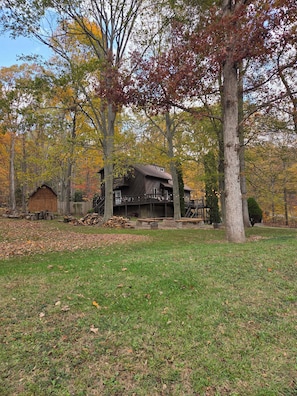 Eine rustikale Holzhütte mit einer Veranda, umgeben von Bäumen mit Herbstlaub.