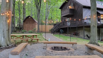 Un chalet rustique doté d’une terrasse en bois et d’un espace aménagé pour faire un feu de camp.