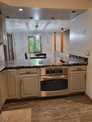 Eine moderne Küche mit Backofen aus Edelstahl, einer Arbeitsplatte aus Granit und beigen Schränken.