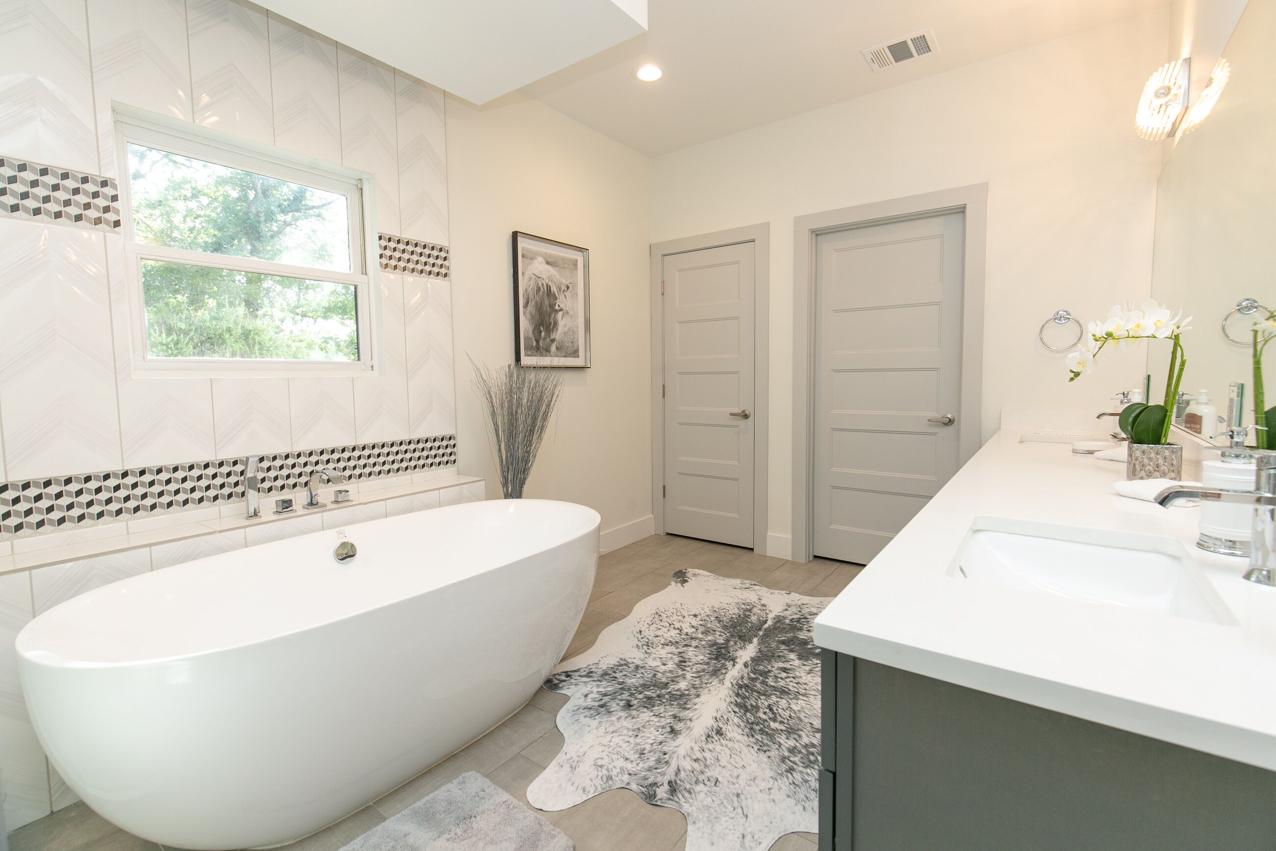 A modern bathroom with a freestanding bathtub, a large mirror, and a white vanity.