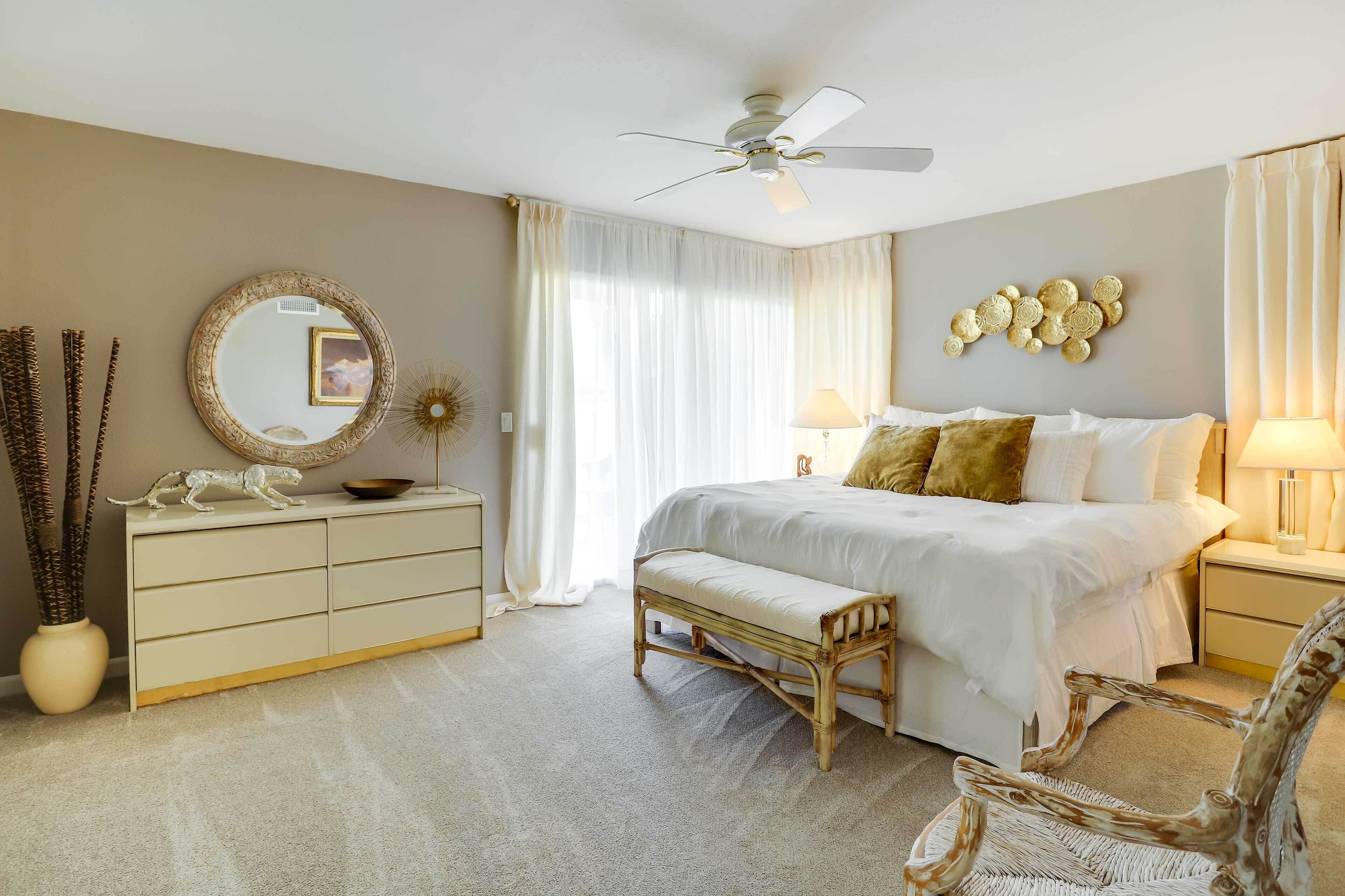 A bedroom with a bed, bedside tables, a mirror, a dresser, a bench, and a chair.