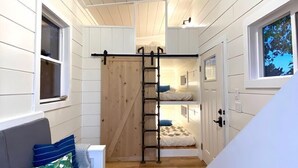 A narrow hallway with a wooden floor, a ceiling fan, and a staircase leading to an upper level. - Cache Vista Tiny |Stunning Teton Views Cozy Retreat (Tetonia)