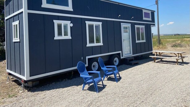 A mobile home with a small porch, two blue chairs, and a picnic table. - Fall Rates- Stay Tiny, Dream Big~Tiny Timber House (Driggs)