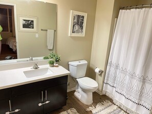 A bathroom with a white sink, black cabinets, a toilet, and a shower curtain. - 2 bedroom apartment in Playa Vista (Los Angeles)