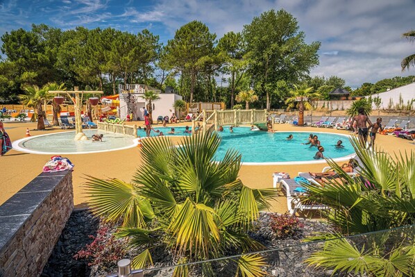 A pool area with multiple pools, lounge chairs, and palm trees.