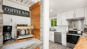 A modern kitchen with white cabinets, a built-in oven, and a coffee bar with a coffee machine and utensils. - Spacious & Modern 3 Bedroom in Madison Valley (Seattle)