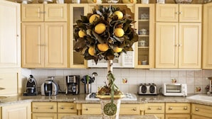 A kitchen with light wooden cabinets, a granite countertop, and a vase with lemons and leaves.