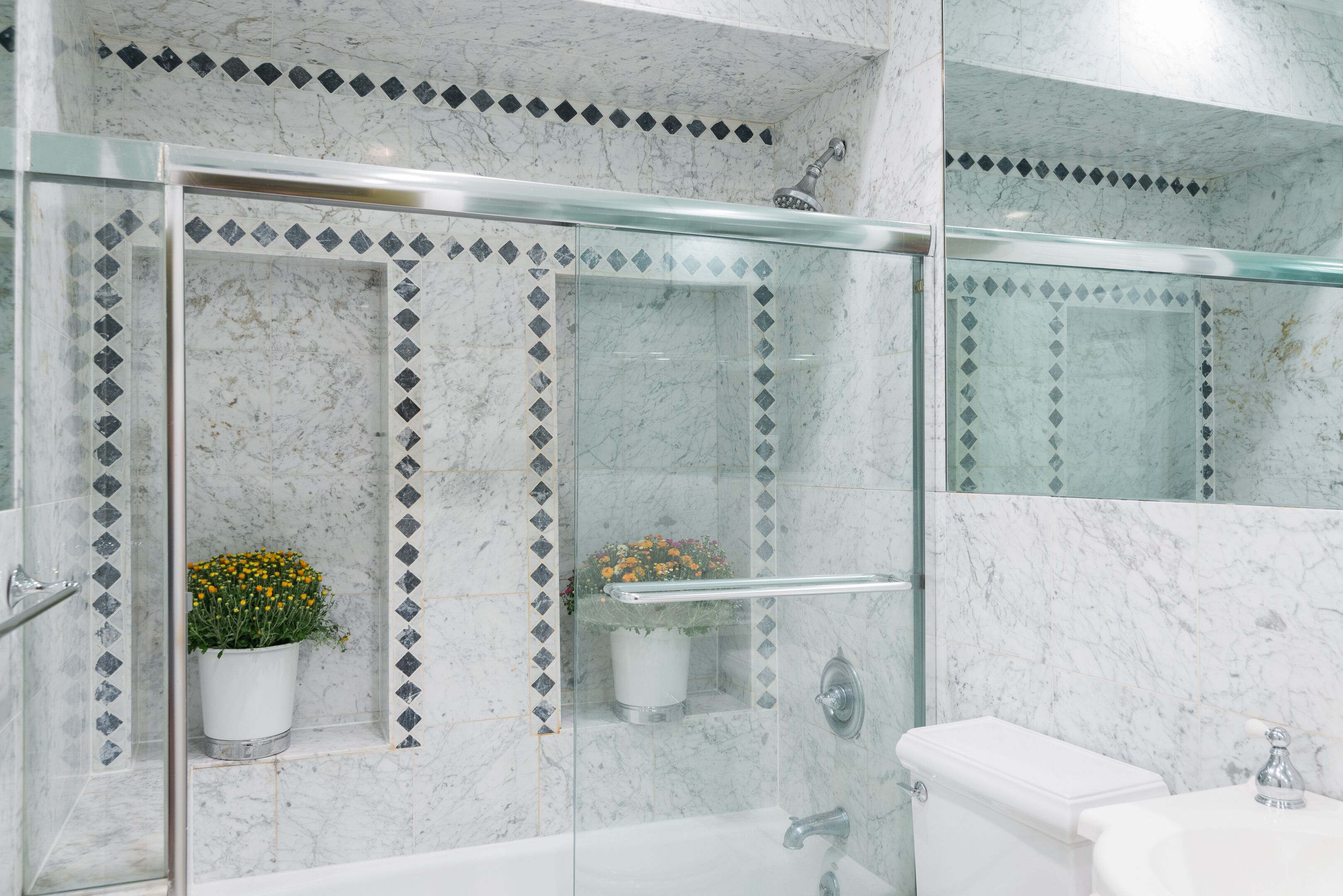 Een badkamer met een douchecabine van glas, een wit toilet en een wastafel.
