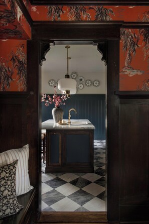 A kitchen with a marble countertop, a sink, and a vase with flowers. - The Craft House Inn (Santa Barbara)