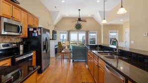 A modern kitchen with wooden cabinets, stainless steel appliances, and a large island. - Footloose & Fab-Semi-oceanfront, pool, hot tub, rec room, pool table, elevator! (Nags Head)