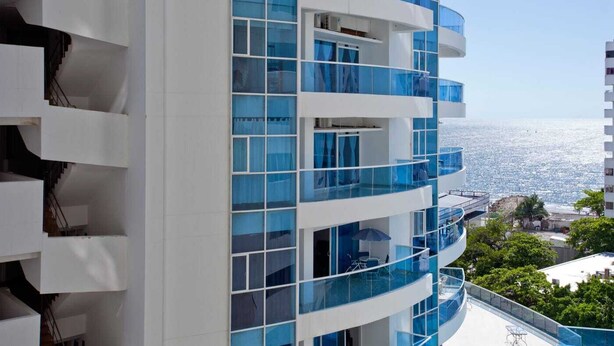 A multi-story hotel with balconies overlooking a coastal view.