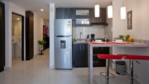 A modern kitchen with a stainless steel refrigerator, dark cabinets, a granite countertop, and pendant lighting.