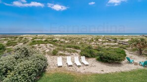 A beach with white lounge chairs and a wooden walkway. - Newly Listed! Welcome to this stunning oceanfront getaway! Magnificent 3 bedroom, 2 bathroom home! (Fernandina Beach)